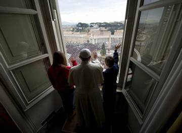 Pope Francis waves with children after he delivered the Angelus prayer at the Vatican